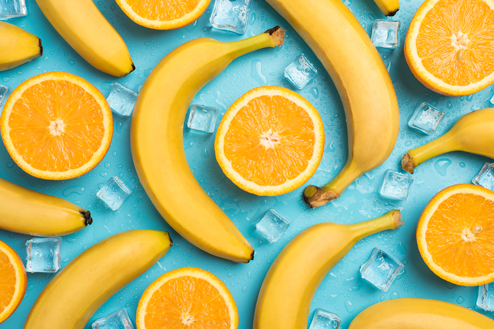 Image illustration of bananas and sliced orange lying together on a blue tablecloth